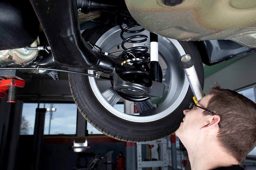 Mechanic is checking the shock absorbers of a modern car